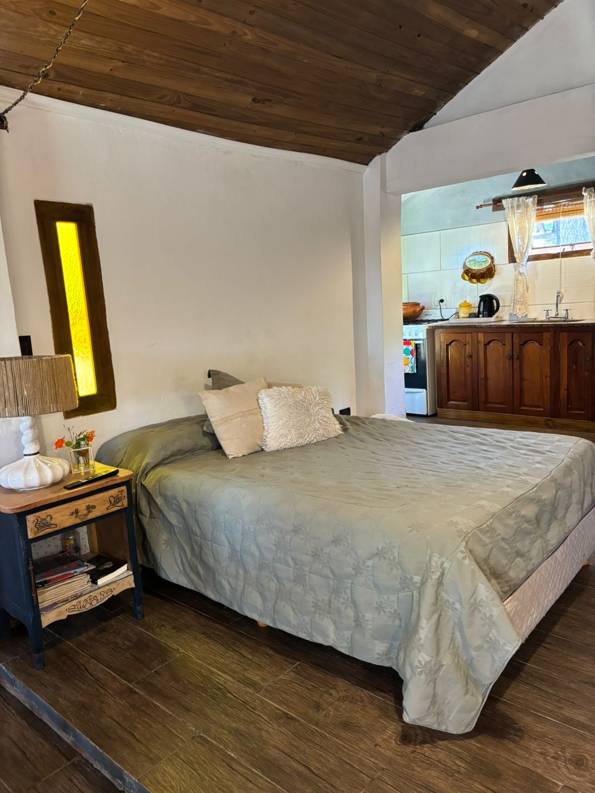 Cama matrimonial con mesa de luz y vista a la cocina