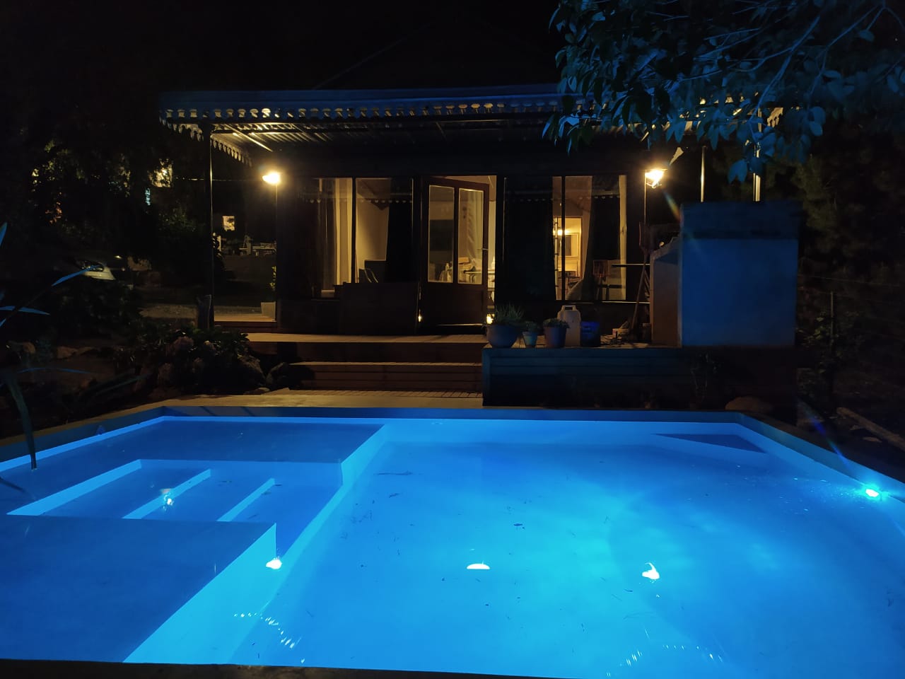 Pileta iluminada de noche frente a la cabaña Entre Sierras